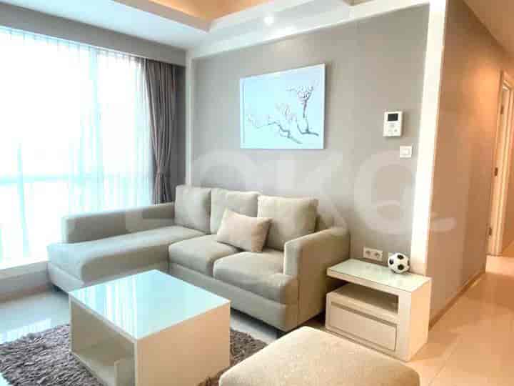 Ruang tamu yang terang benderang dengan sofa berbentuk L besar, meja kopi persegi, dan lemari.