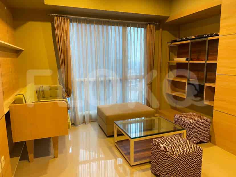 A modern living room with a sofa, ottoman, coffee table, and built-in shelving.