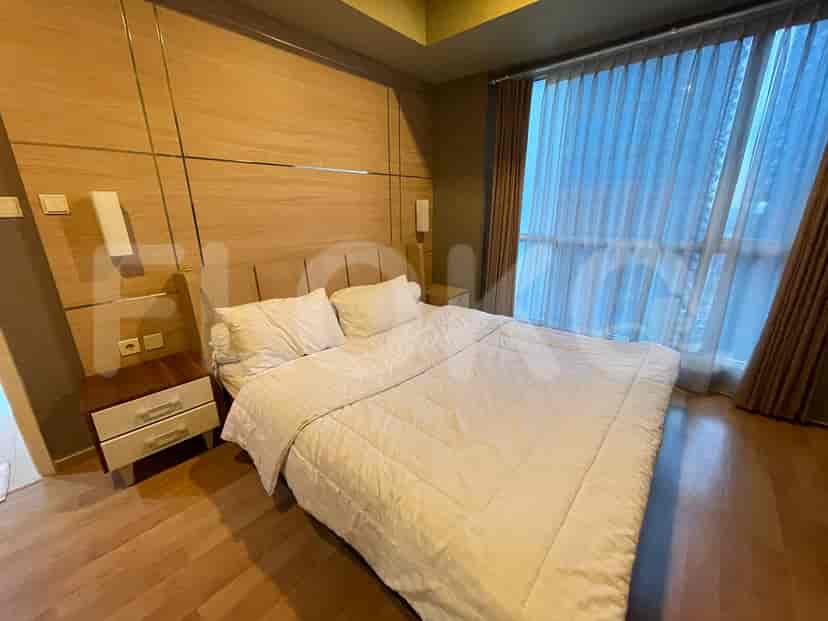 A bedroom with a bed, nightstands, and large windows.