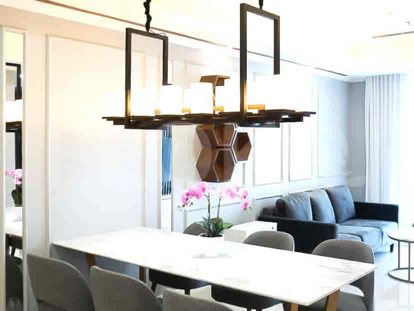 Elegant dining area with a marble-topped table, upholstered chairs, and a decorative chandelier.