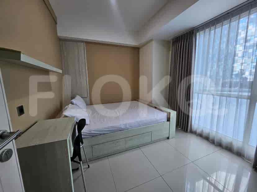 A bedroom with a bed, a desk, and a window.