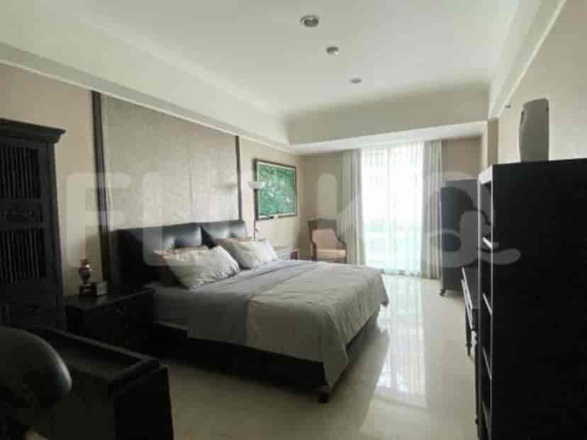 Spacious bedroom with a bed, dark wooden furniture, and large windows with curtains.