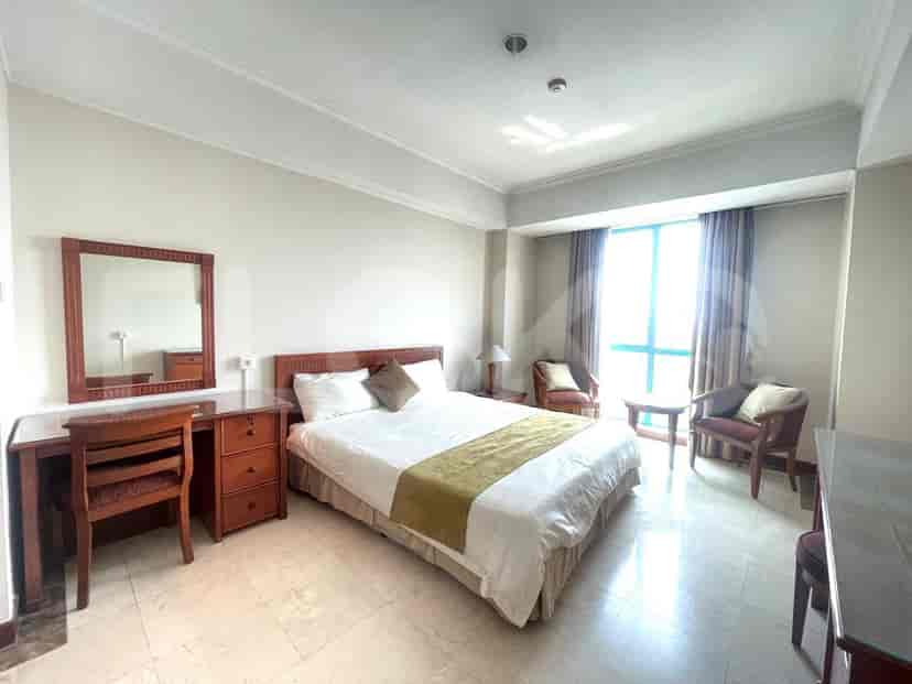 Bedroom with a bed, a desk, and a large window.