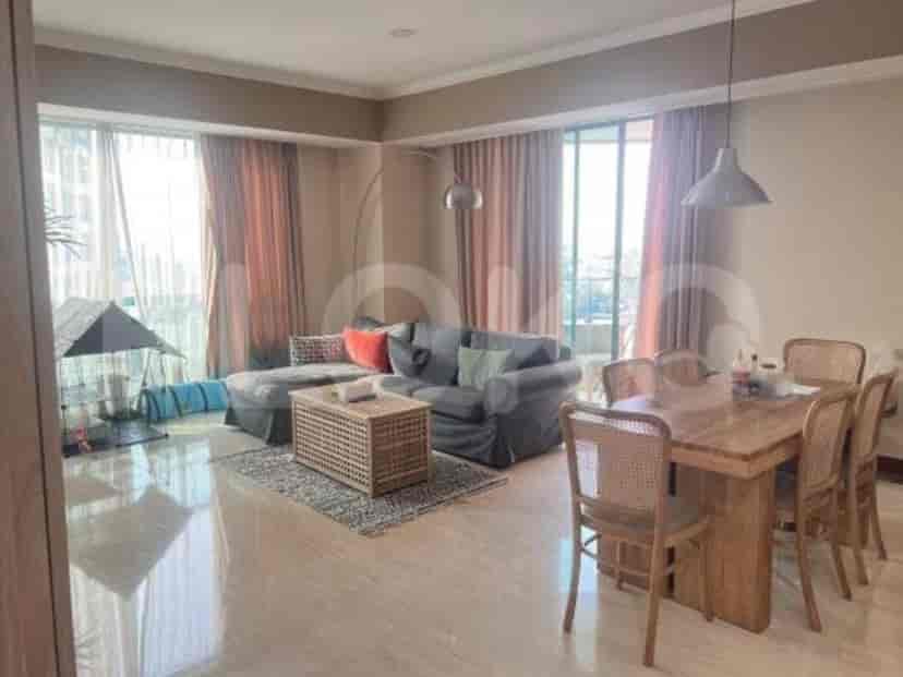 A well-lit living room featuring a comfortable L-shaped sofa, a stylish dining table, and large windows offering ample natural light.
