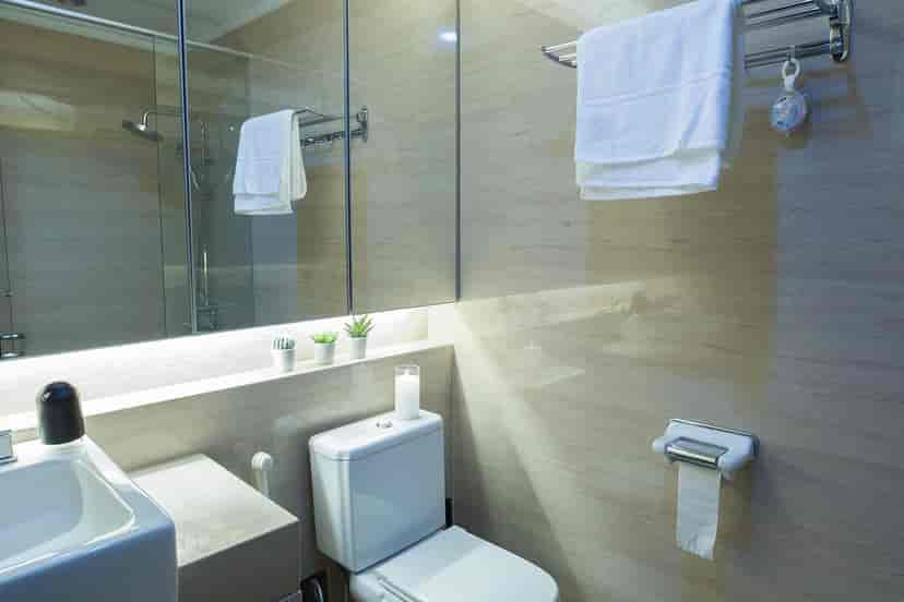A clean, modern bathroom with a toilet, sink, and mirror.