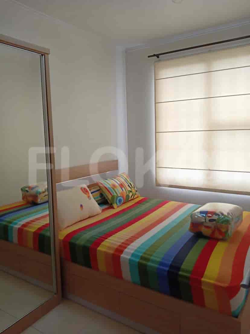 Kamar tidur yang menampilkan tempat tidur ganda dengan seprai berwarna-warni dan lemari bercermin.