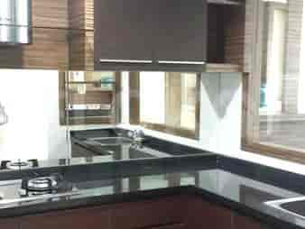 Kitchen with stainless steel hood, cabinets, and black countertop.