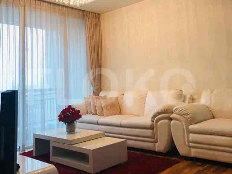 Living room with a white sofa, coffee table, and large windows.