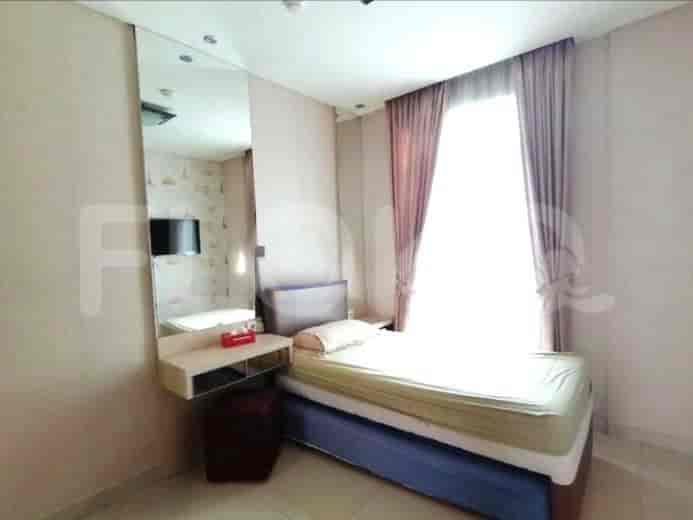 A bedroom with a single bed, a mirror, and a small vanity area.