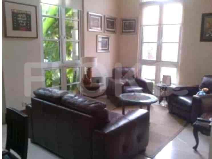Ruang tamu dengan sofa kulit dan kursi berlengan dengan jendela di samping.