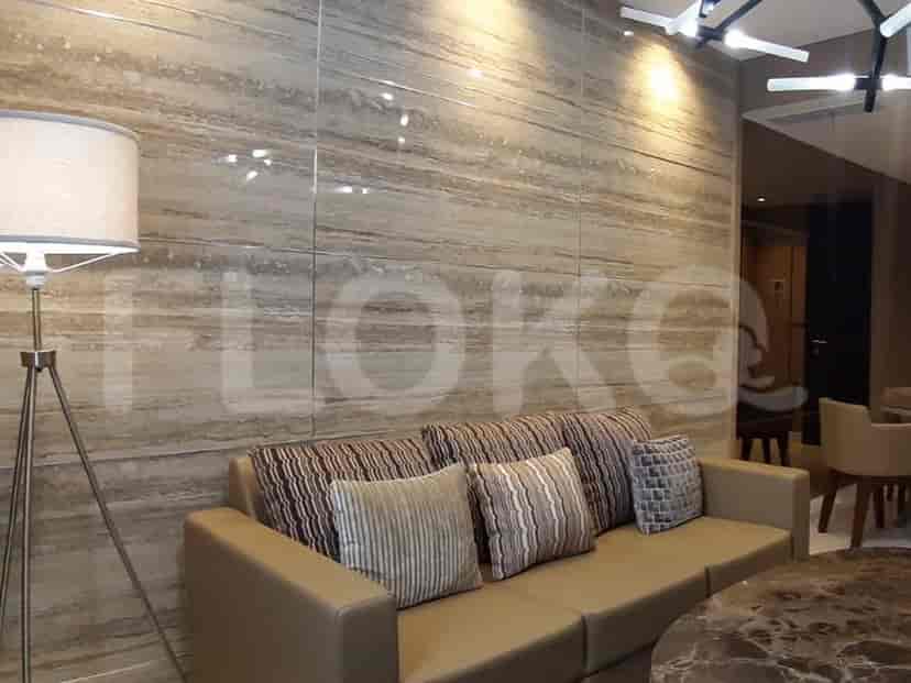 A living room featuring a beige sofa, patterned accent wall, and a floor lamp.