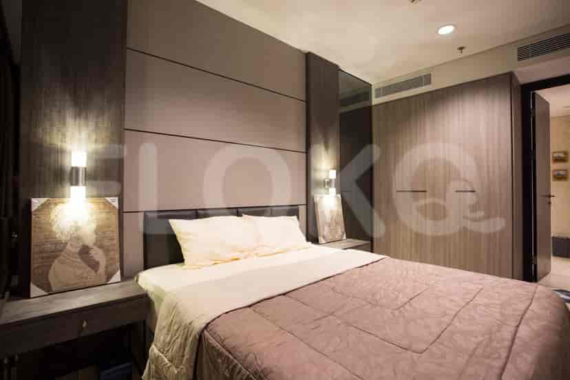 A modern bedroom with a large bed, dark wooden panels, and ambient lighting.