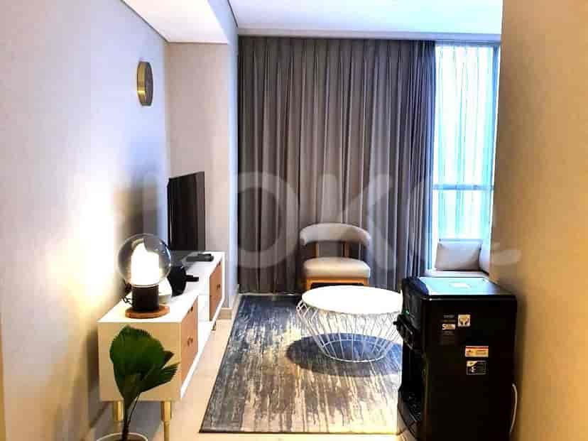 Cozy living area with a white coffee table, wall-mounted TV, and a small seating area.