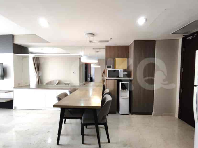 A modern kitchen and dining area with a wooden dining table, kitchen appliances, and a large mirror.