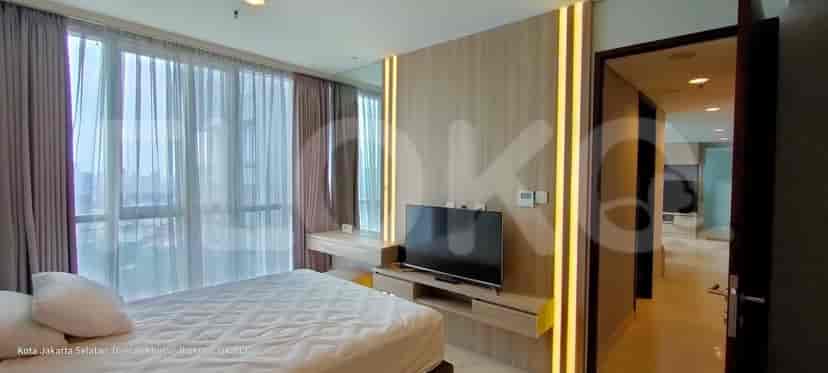 A modern bedroom with a bed, a TV, and large windows.