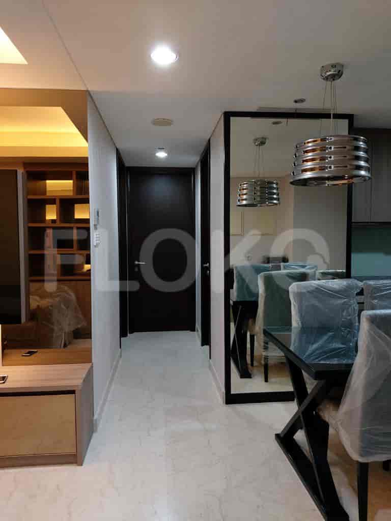 A hallway connecting different rooms, featuring a dining area, a mirrored wall, and a dark door.
