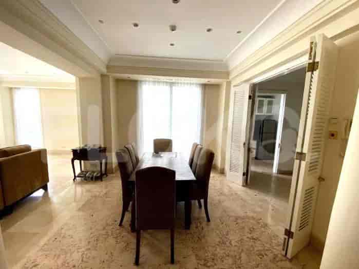 Dining room with a large dining table and chairs, and a view towards the kitchen.