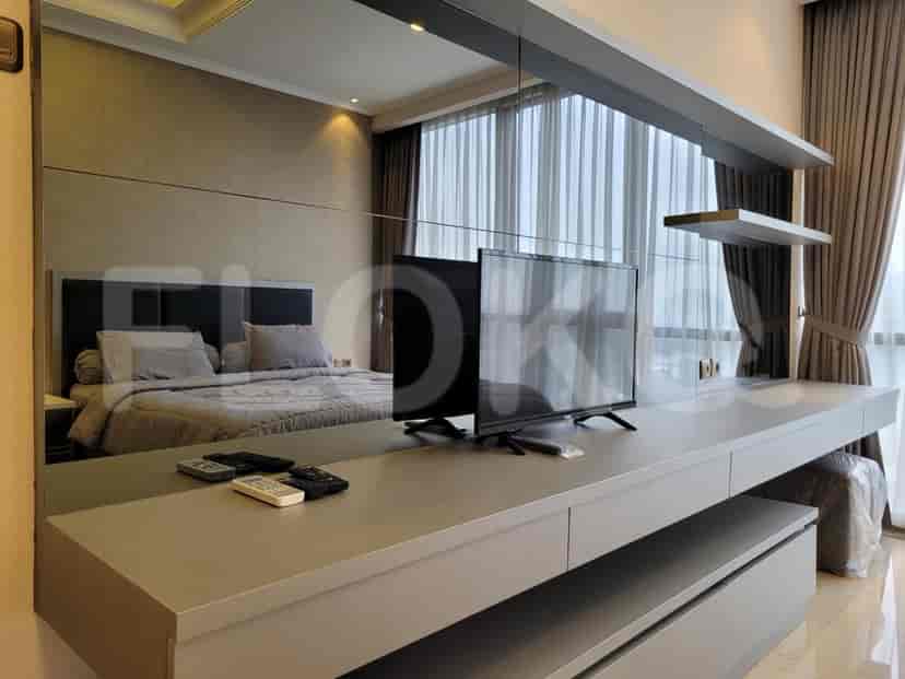 A bedroom with a bed, large mirror, dresser and a flat-screen TV.