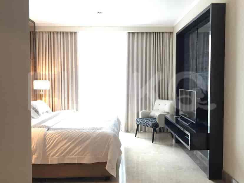 A bedroom featuring a bed, armchair, and TV setup.