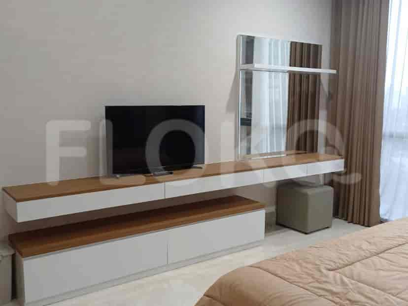 Wall-mounted TV, mirror, and storage unit in a bedroom.