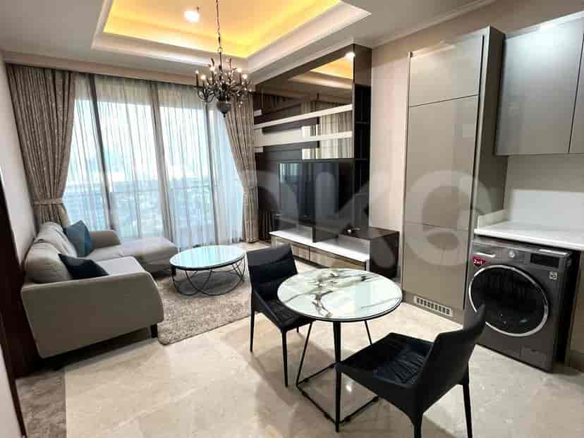 A modern living space with a combined kitchen area, featuring a grey sofa, dining table, and integrated appliances.