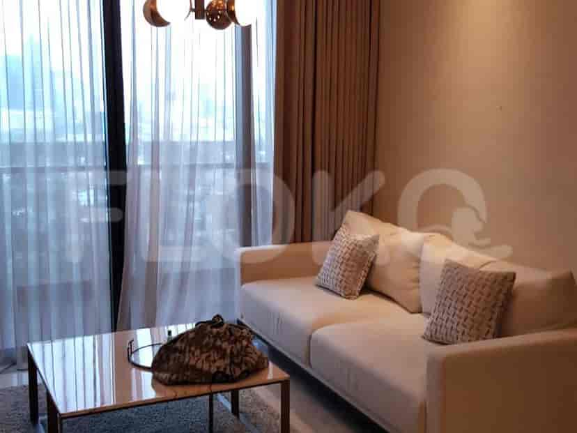 Another view of the living room with a cream sofa, sheer curtains, and a coffee table.