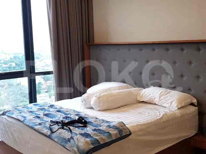A bedroom featuring a bed with a grey headboard and large windows.