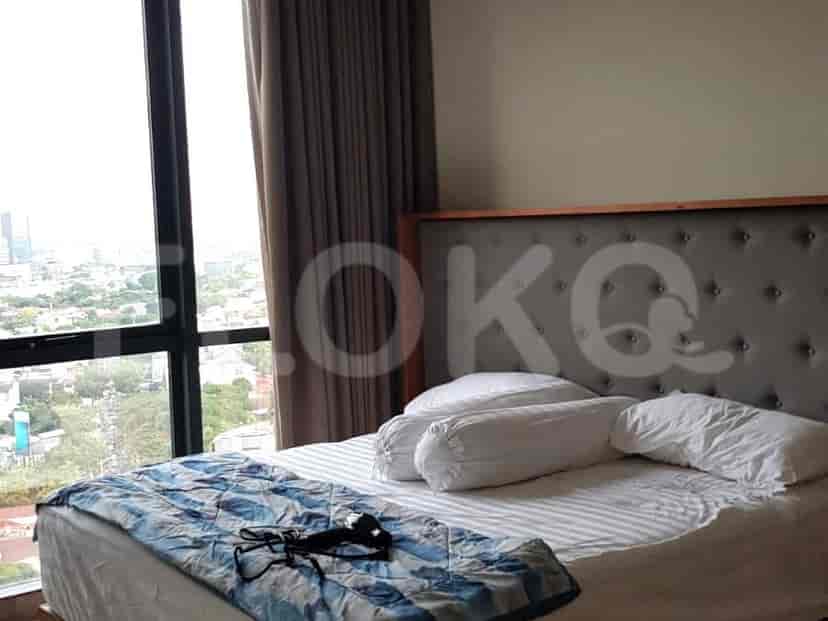 A bedroom with a bed, large windows, and a view of the city.