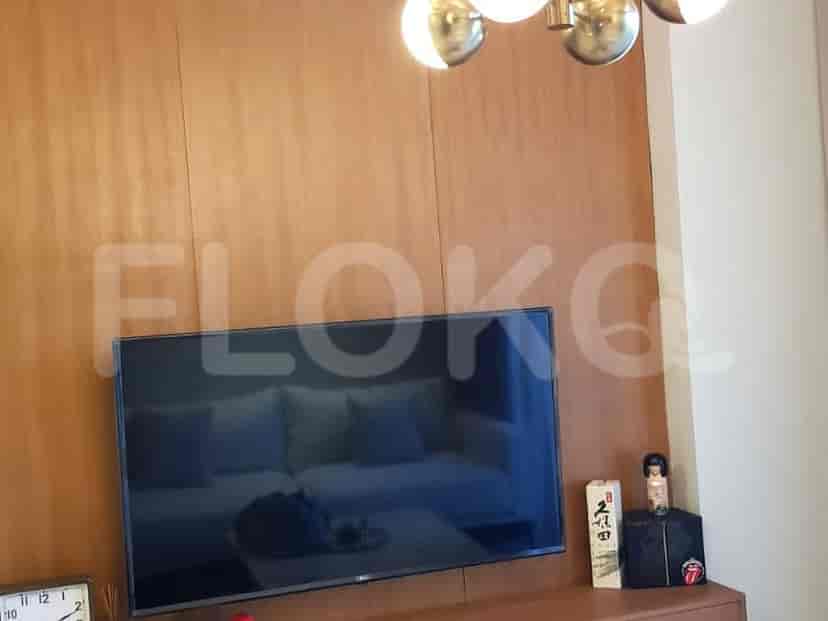 A living room with a wall-mounted TV and a modern chandelier.