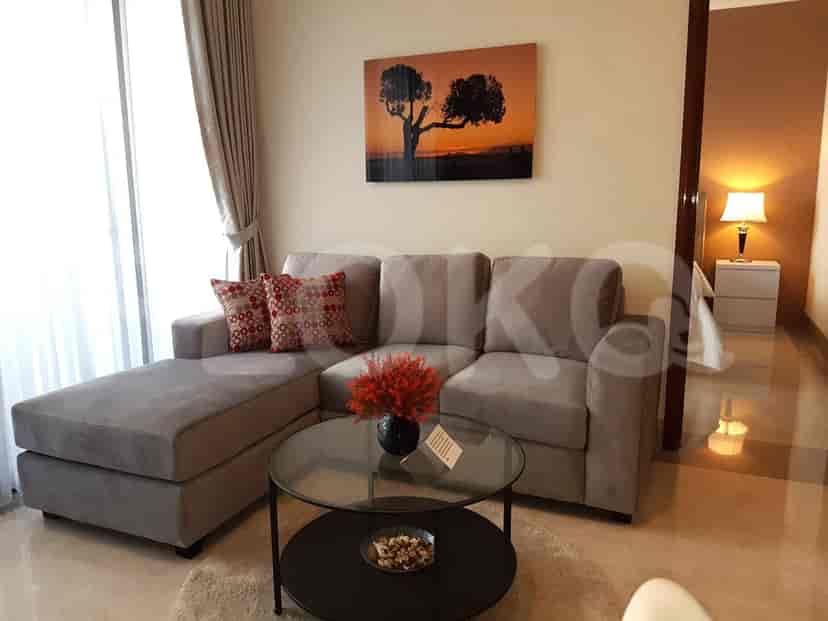 Living room with a grey sectional sofa, round glass coffee table, and artwork.
