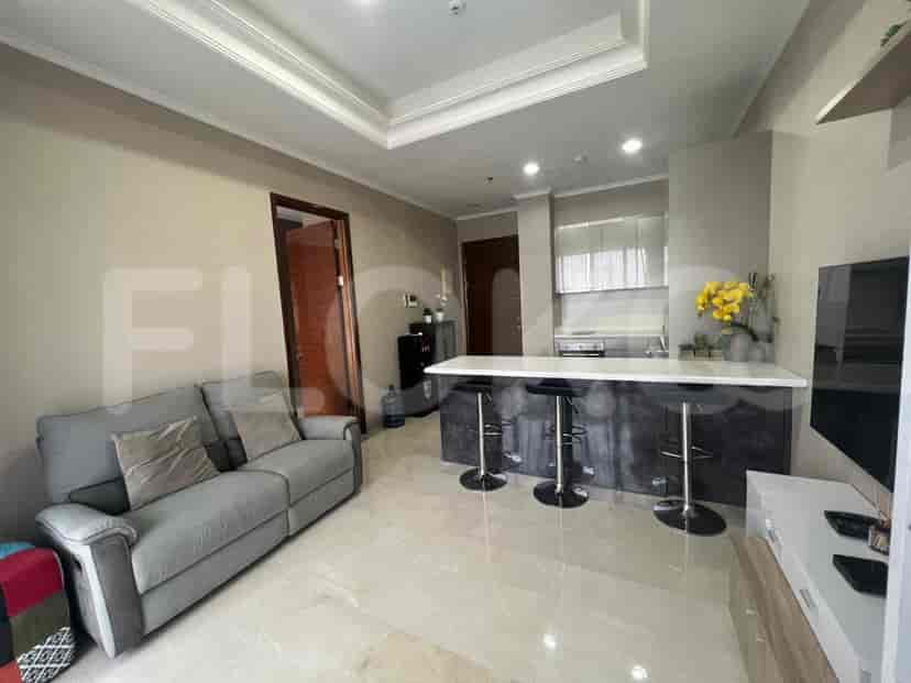 Open-plan living area with a grey sofa, kitchen island with bar stools, and open kitchen.
