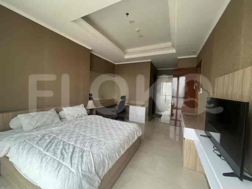 Bedroom with a large bed, a desk, and a smart TV, featuring a city view from the window.