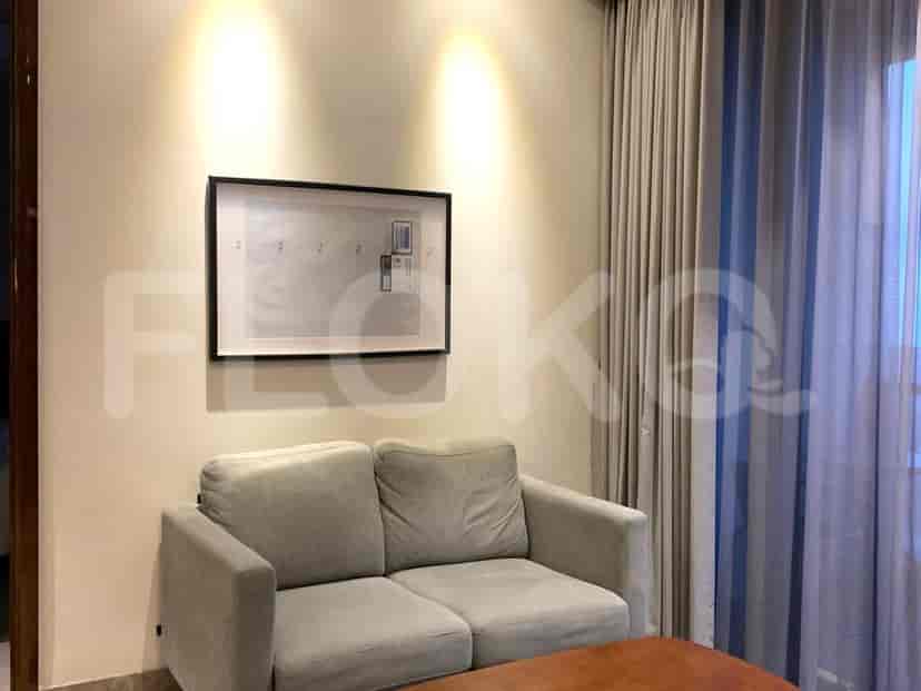 A living area with a grey sofa, artwork, and curtained window.