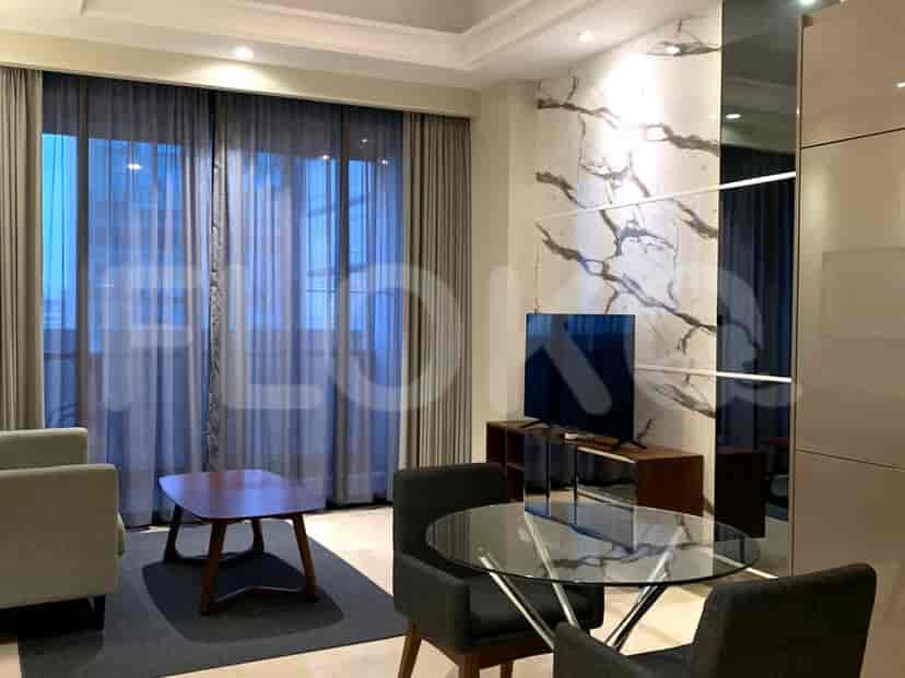 Living area with a modern layout, featuring a table, seating, and a TV.