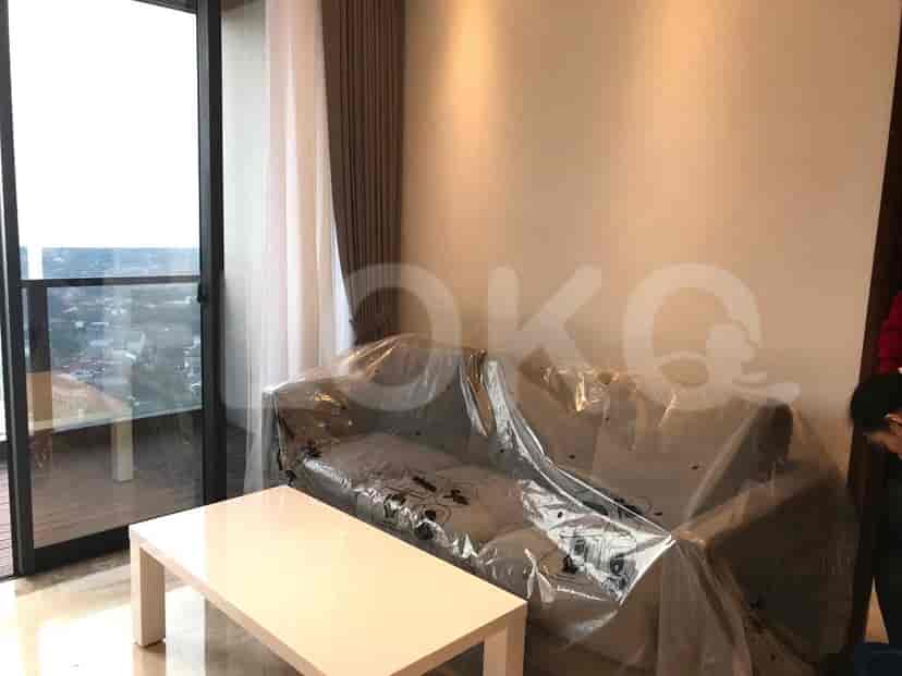 A living room with a sofa covered in plastic, a white coffee table, and a balcony.