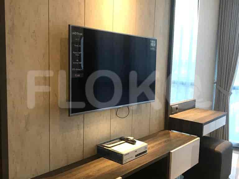 A wall-mounted TV with a wooden console and a side table.
