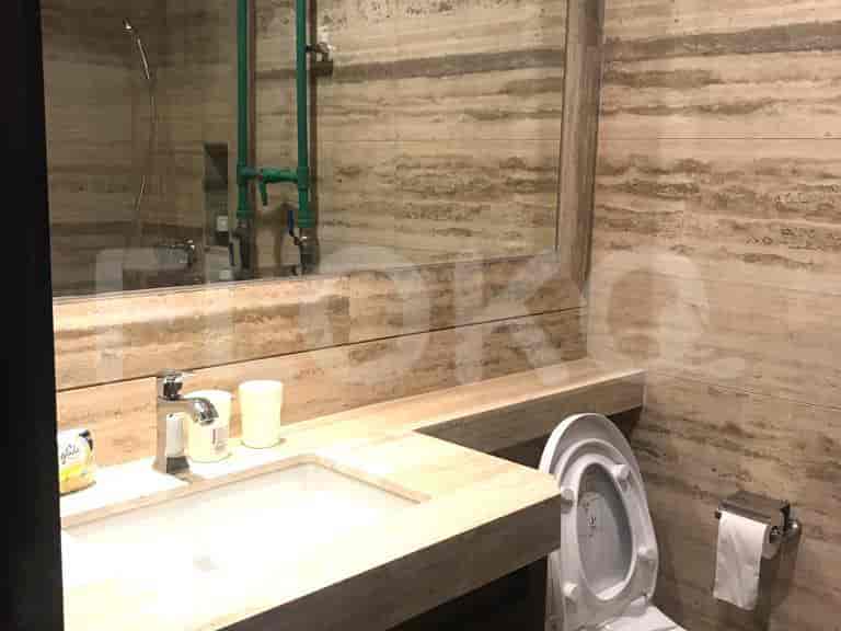 A modern bathroom featuring a stone vanity, a mirror, and a toilet.