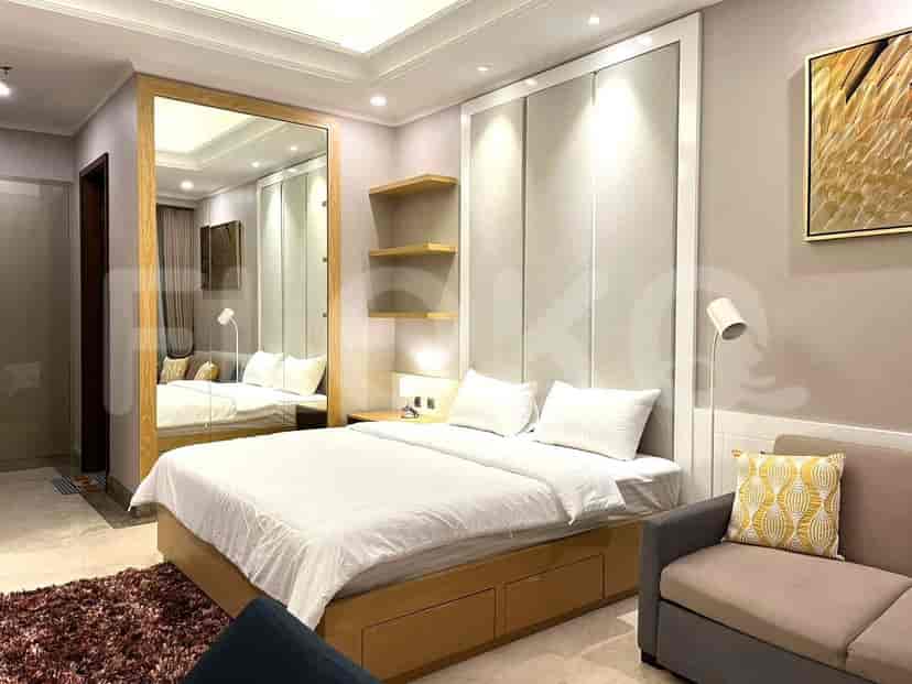 A bedroom with a large bed, a sofa, and a large mirror.