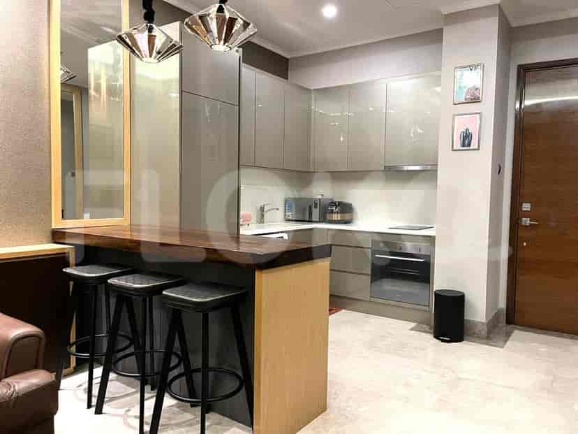 A modern kitchen with grey cabinets, a breakfast bar, and stools.