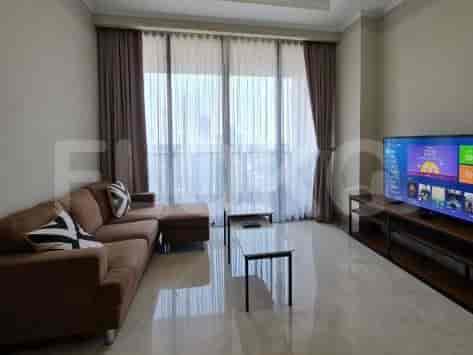 A modern living room with a sofa, TV, and large windows.