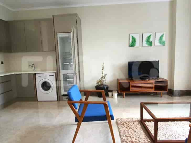 A living room with a blue chair, a television, and a kitchen area visible.