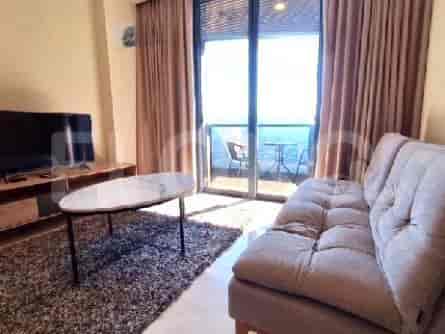 A modern living room with a sofa, coffee table, TV, and balcony access.