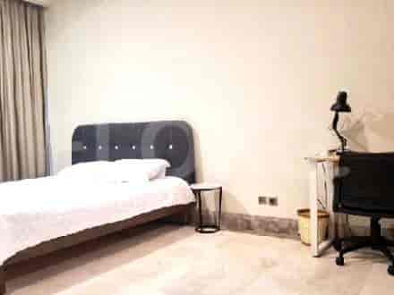 A minimalist bedroom with a bed, desk, and neutral color scheme.