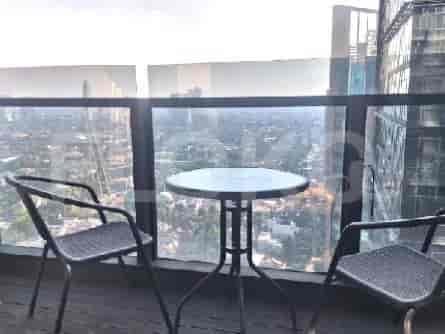 A balcony with chairs and a table overlooking a city view.