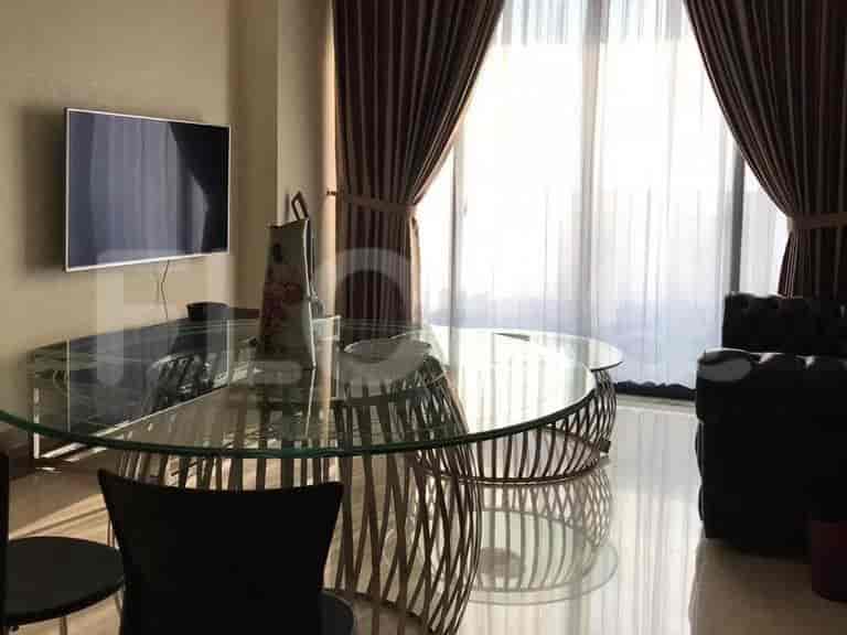 Elegant living room with glass dining table, TV, and large windows.