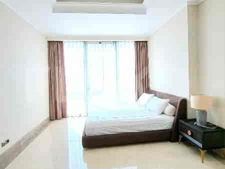 Spacious bedroom with a large bed and window.
