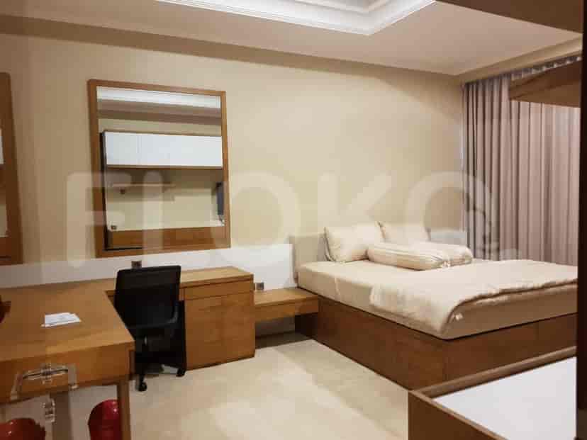 Spacious bedroom with a wooden bed frame, desk, and large mirror.
