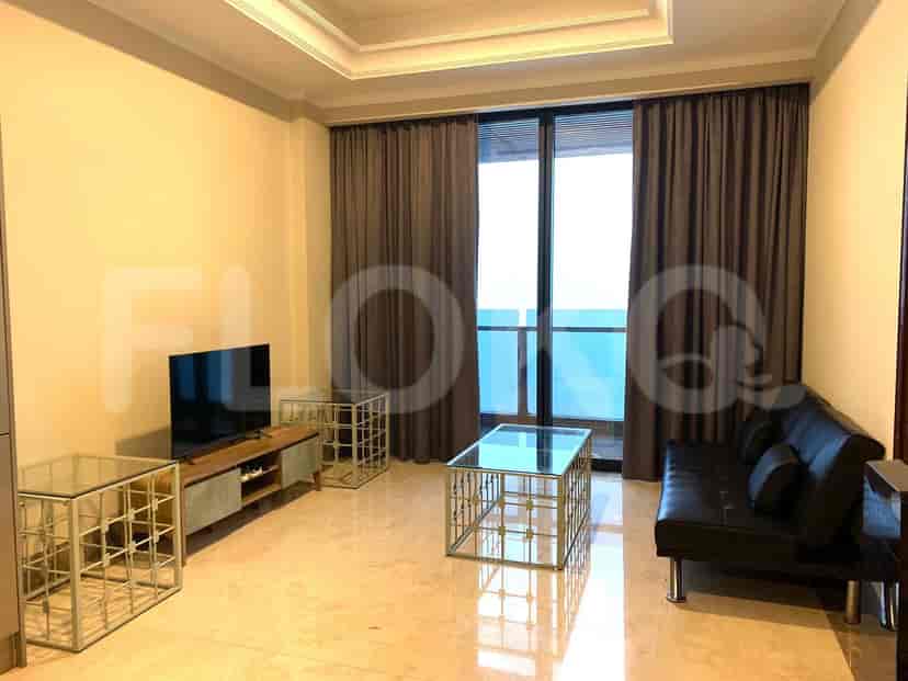Modern living room with black leather sofa, glass coffee table, and TV setup.