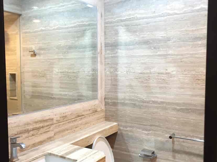 Bathroom with a sink, mirror, and stone-like tiles.