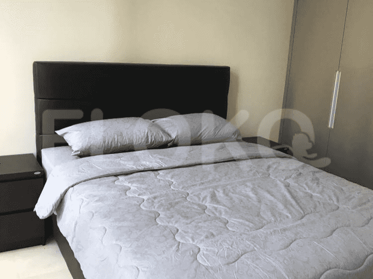 Kamar tidur dengan tempat tidur, meja samping tempat tidur, dan lemari pakaian.